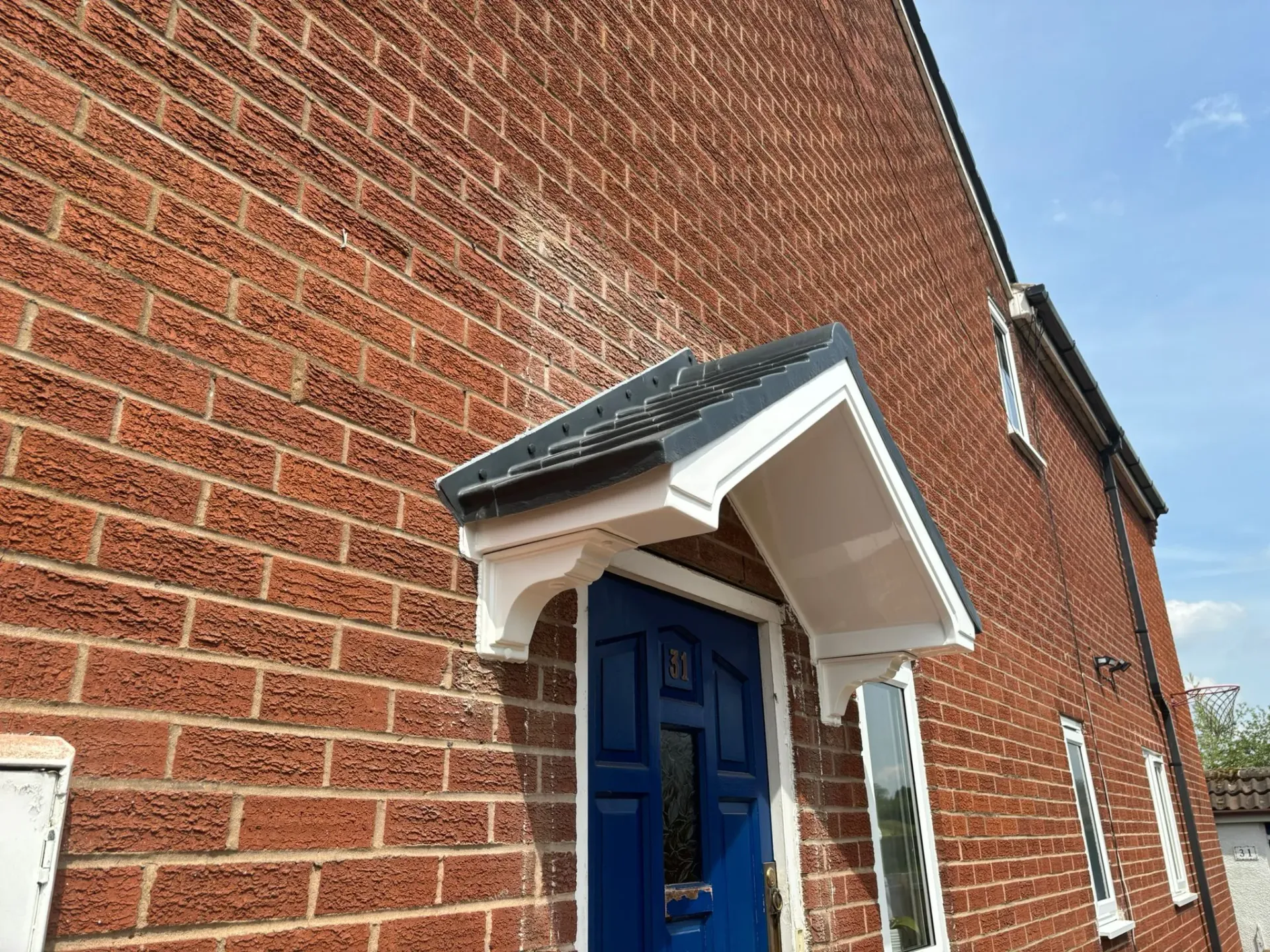 A newly installed pitched door canopy on a red brick residential property