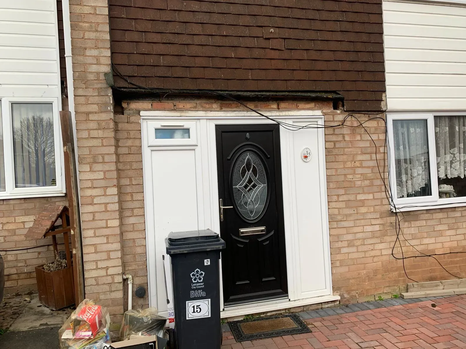 A picture showing damaged hanging tiles and exposed brickwork above a residential front door.
